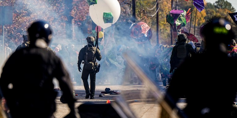 Police officers confront protesters in a gas cloud during a demonstration in opposition to a new police training center, Monday, Nov. 13, 2023, in Atlanta. (AP Photo/Mike Stewart)