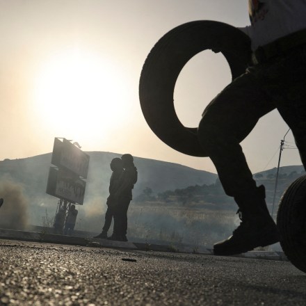 Palestinian protesters roll tires to be burned during clashes with Israeli forces at the Israeli-controlled Huwara checkpoint near Nablus in the occupied West Bank on May 29, 2022.